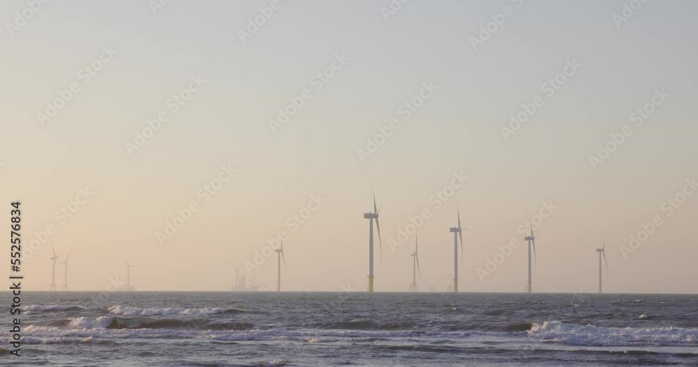 Large wind turbines producing plant on the sea under sunset Large wind turbines producing plant on the sea under sunset