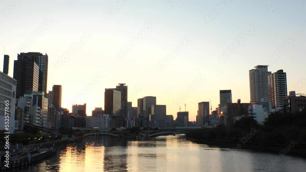 OSAKA, JAPAN - SEP 2022 : View of office buildings at Kitahama area and river in sunset. Large business district in Osaka. Japanese business, company, real estate and urban city concept video. OSAKA, JAPAN - SEP 2022 : View of office buildings at Kitahama area and river in sunset. Large business district in Osaka. Japanese business, company, real estate and urban city concept video.
