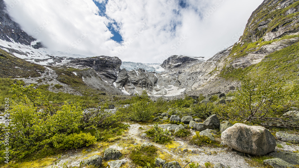 Idyllic hiking trail through the norwegian fauna to the impressive Jostedalsbreen glacier on a rainy day