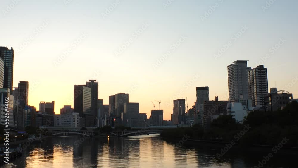OSAKA, JAPAN - SEP 2022 : Office buildings at Kitahama area and river in sunset. Large business district in Osaka. Time lapse shot, dusk to night. Japanese business, company and urban city concept. OSAKA, JAPAN - SEP 2022 : Office buildings at Kitahama area and river in sunset. Large business district in Osaka. Time lapse shot, dusk to night. Japanese business, company and urban city concept.
