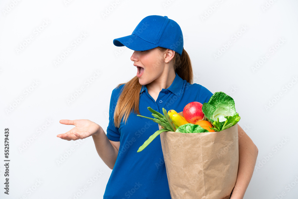 Young delivery woman taking a bag of takeaway food isolated on white background with surprise expression while looking side Young delivery woman taking a bag of takeaway food isolated on white background with surprise expression while looking side