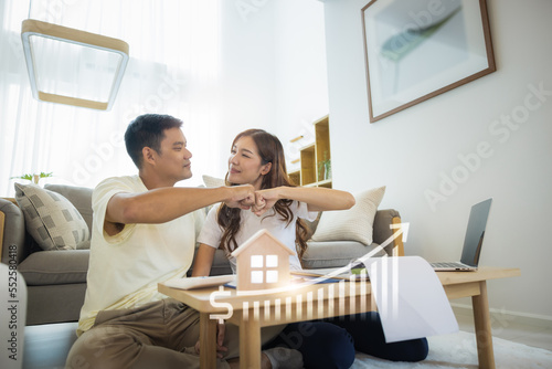 Asian couple in home or house. Include increasing graph, laptop, calculator and document on table. To bump punch with concept for market price, house value, loan, finance, real estate and property. 