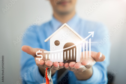 Businessman, salesman to hold model of home, house. Include increase graph or chart of price forecast. To offer for sale, investment. Concept for value, income, wealth, asset, real estate and property photo