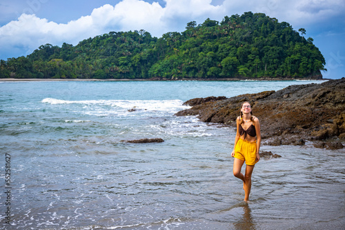 A beautiful girl in yellow shorts walks on a tropical beach with palm trees in manuel antonio national park in quepos, Costa Rica; tropical paradise beach in Costa Rica