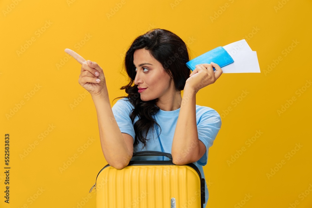 Traveler woman with yellow suitcase, passport and ticket in hand, paper plane, blue t-shirt and jeans on yellow background tourist, travel happiness, glasses, copy space Traveler woman with yellow suitcase, passport and ticket in hand, paper plane, blue t-shirt and jeans on yellow background tourist, travel happiness, glasses, copy space