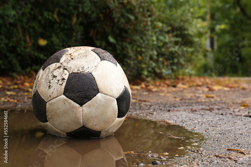 Dirty soccer ball in muddy puddle, space for text © New Africa
