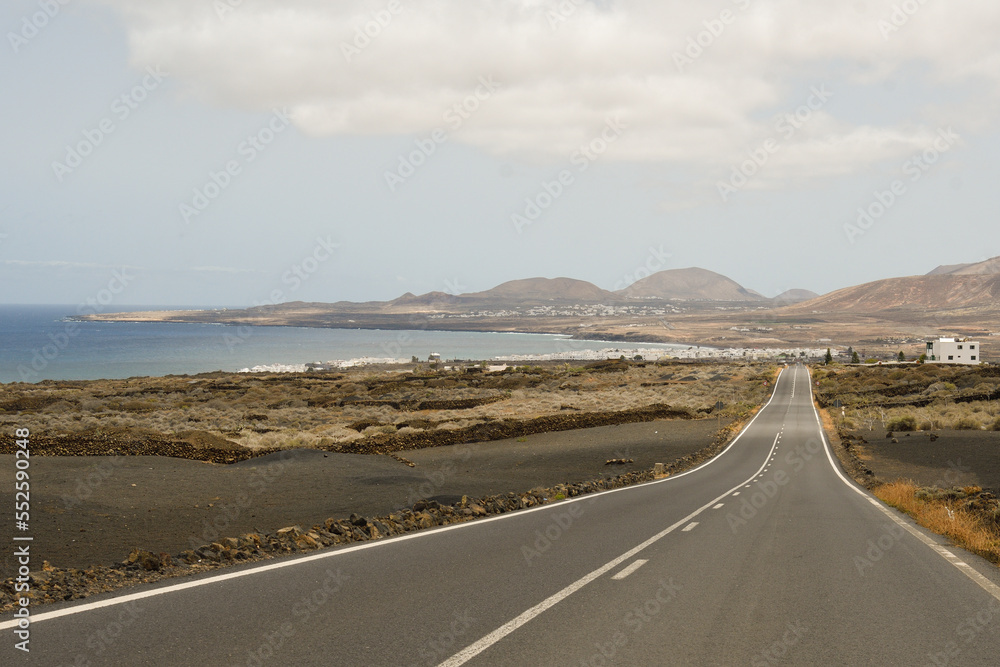 Road between tabaibas with Punta Mujeres in the background