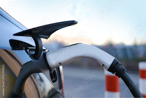 Foto close-up adapter with electric vehicle cables, part of black car charging energy