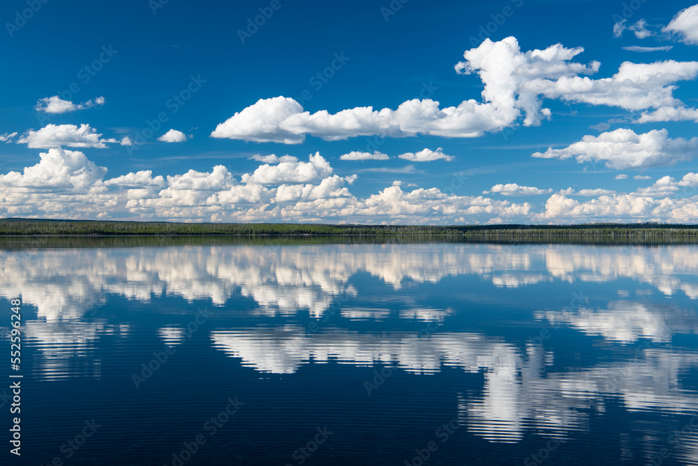 Tranquil scene of blue sky with white clouds reflected in a calm, peaceful lake