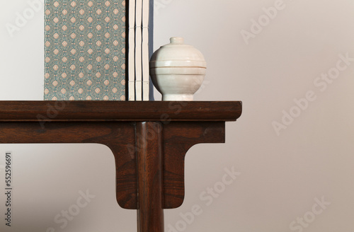 Chinese antique ceramic and traditional style book on wooden table against white wall