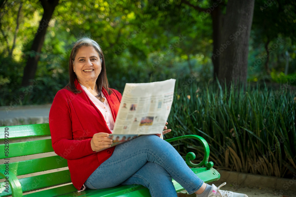 Senior Indian woman reading newspaper at park. Senior Indian woman reading newspaper at park.