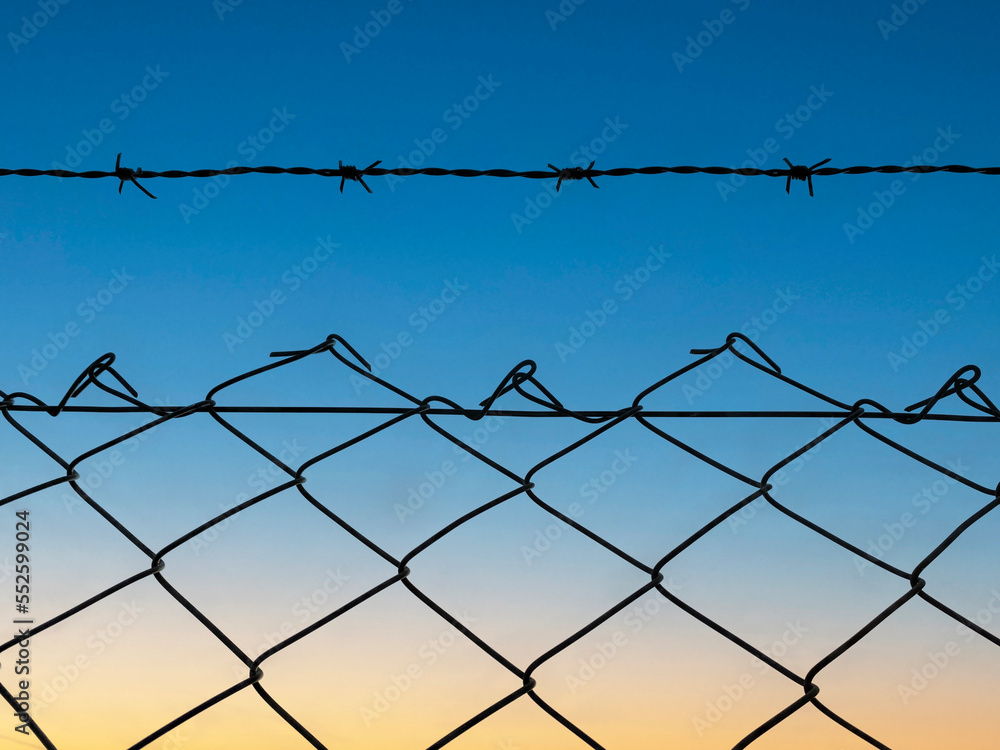 barbed wire against the sunset. barbed wire on the fence of the fenced territory. barbed wire against the sunset. barbed wire on the fence of the fenced territory.