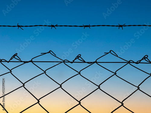 barbed wire against the sunset. barbed wire on the fence of the fenced territory.