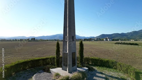 Aerial drone view rising to the top of the Obelisk of Remembrance of Cernay (Upper-Rhine, Alsace, France), with fields, villages and Vosges mountains in background, by sunny summer weather photo