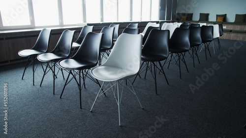Empty loft style conference room with black and white chairs and full wall windows. Audience for conferences and other events.