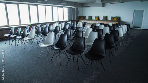 Empty loft style conference room with black and white chairs and full wall windows. Audience for conferences and other events.