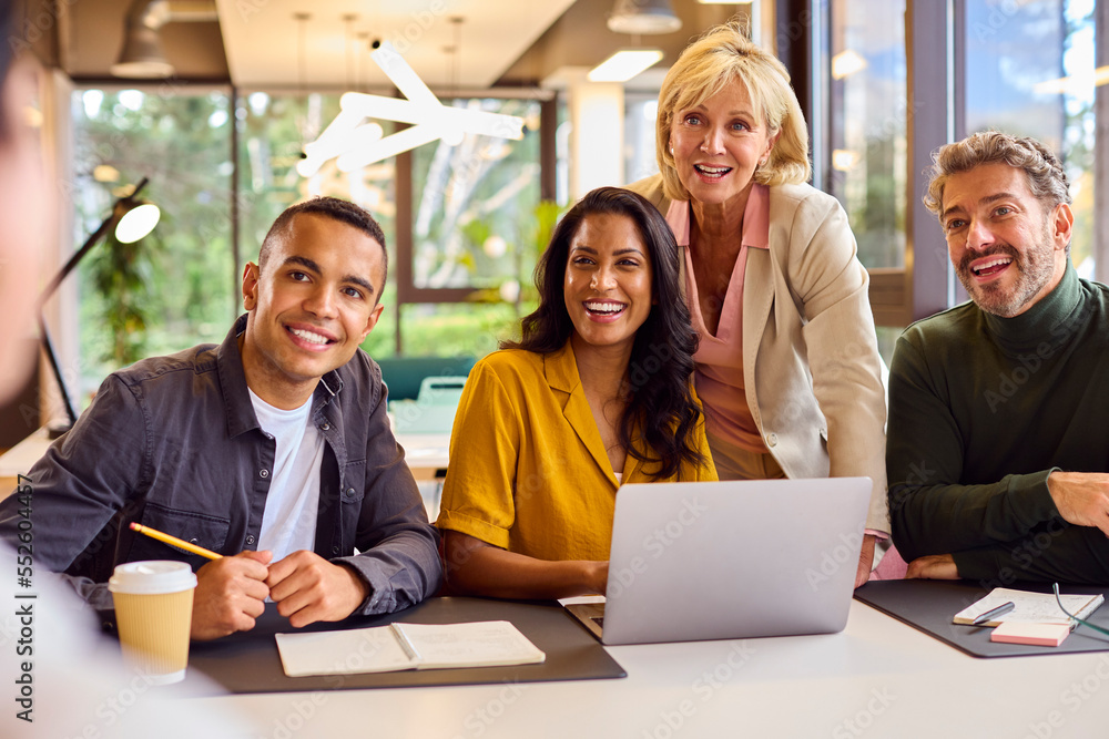 Obraz premium Multi-Cultural Business Team Meeting Around Laptop In Modern Office