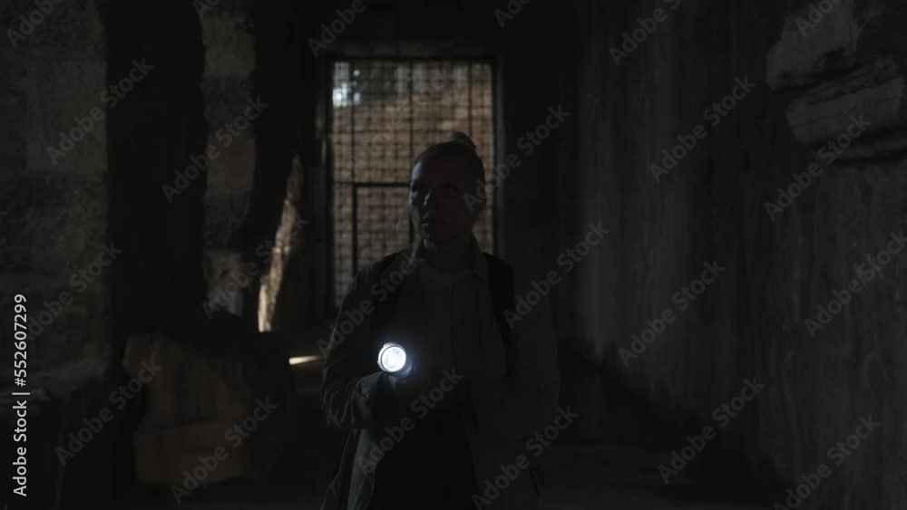 A young female archaeologist walks down a dark corridor to the cell with a flashlight in her hands. High quality 4k footage A young female archaeologist walks down a dark corridor to the cell with a flashlight in her hands. High quality 4k footage