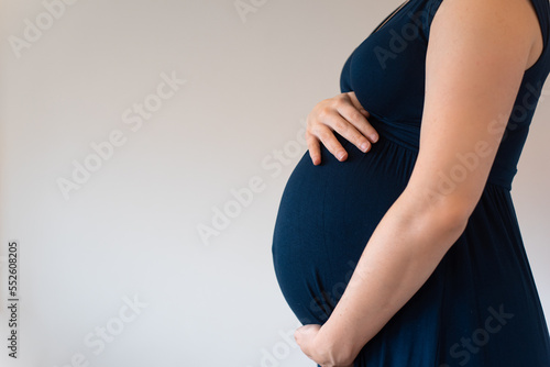 Pregnant woman wearing blue dress holding her belly