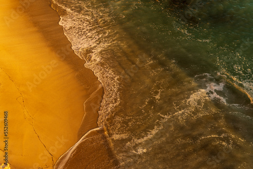 Piękna piaszczysta plaża w promieniach zachodzącego słońca z lotu ptaka, Algarve, Portugalia. 