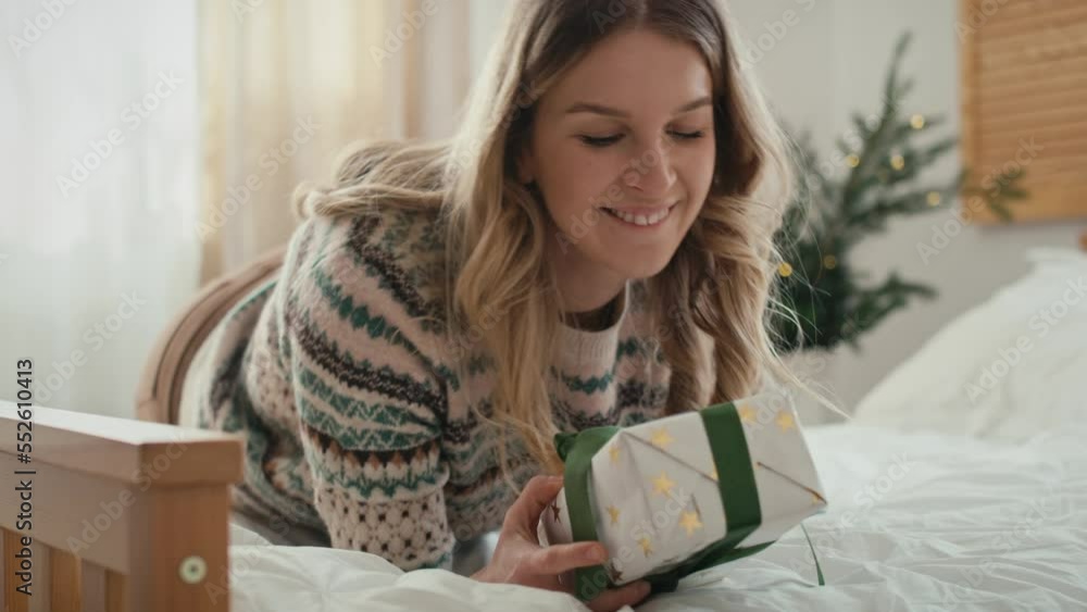 Caucasian woman lying down on bed and opening Christmas present. Shot with RED helium camera in 8K. Caucasian woman lying down on bed and opening Christmas present. Shot with RED helium camera in 8K.