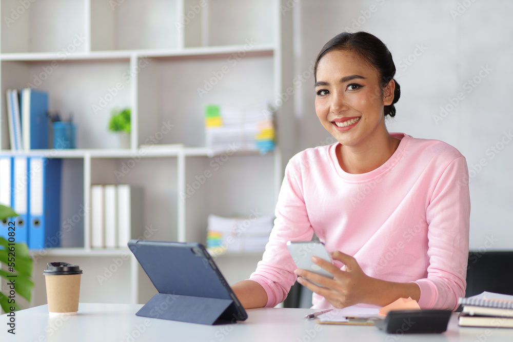 Woman in home office using tablet and mobile phone writing work schedule on notepad, Working from home. Woman in home office using tablet and mobile phone writing work schedule on notepad, Working from home.