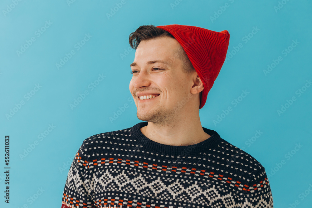 Young man in Christmas sweater and hat on color background. Young man in Christmas sweater and hat on color background.
