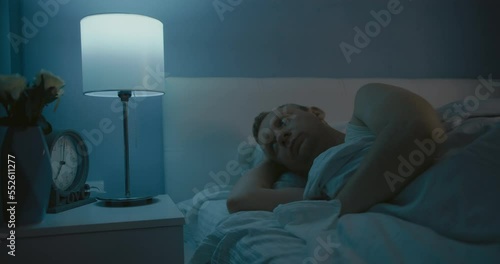 Sleepless night and Insomnia problem. Tired man disturbed with anxiety trying to rest in bed