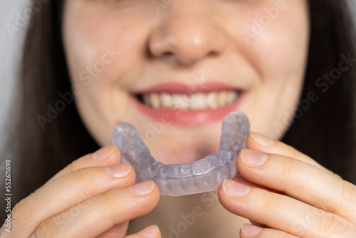 A woman holds dental mouthguard, splint for the treatment of dysfunction of the temporomandibular joints, bruxism, malocclusion, to relax the muscles of the jaw.