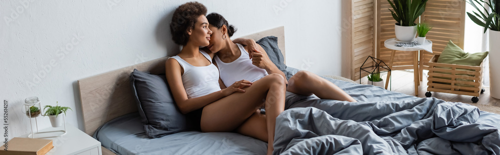 young lesbian african american woman hugging girlfriend in modern bedroom, banner. young lesbian african american woman hugging girlfriend in modern bedroom, banner.