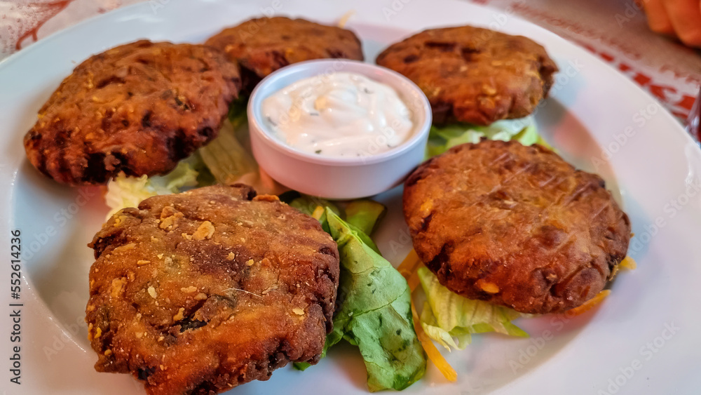 Greek burgers (biftekia) served with white sauce in an authentic restaurant in the streets of Thessaloniki, Central Macedonia, Greece, Europe. Mince meat beef patties in white plate