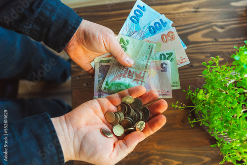 Turkish banknotes in the hands of a man. turkish iron money and paper money at the guy on a wooden background photo