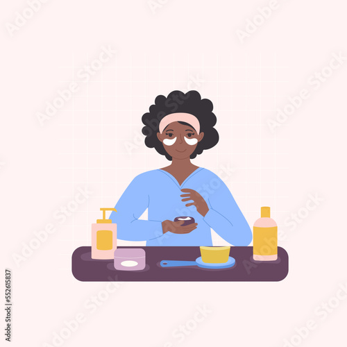 A black African-American woman is in the bathroom applying patches under her eyes.