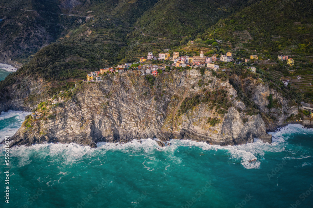 Italy, Liguria, Cinque Terre, Corniglia, Multi colored town architecture among hills. Aerial drone view from the seaside. September 2022