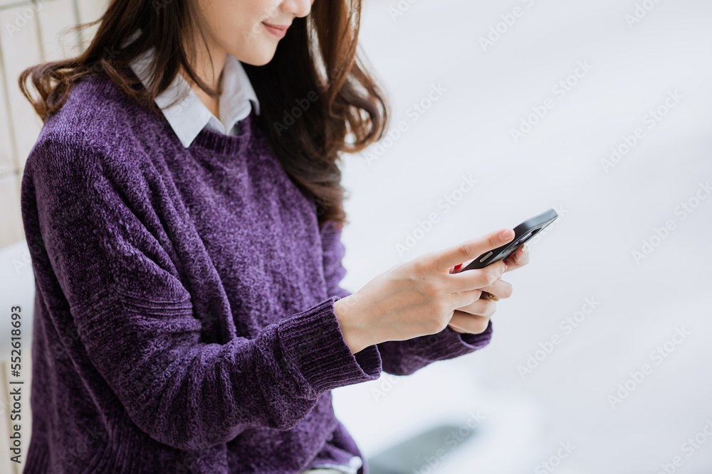 Young Asian woman using smartphone texting with happy face standing smiling confidently. Young Asian woman using smartphone texting with happy face standing smiling confidently.