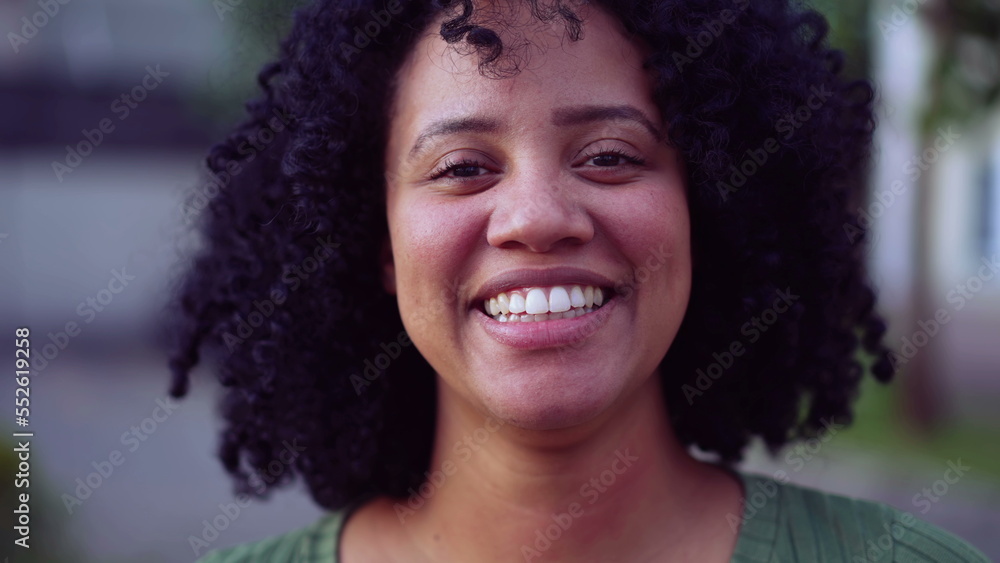 one happy Brazilian black young woman portrait face closeup standing outside looking at camera smiling. African American adult girl female person with joyful emotion one happy Brazilian black young woman portrait face closeup standing outside looking at camera smiling. African American adult girl female person with joyful emotion