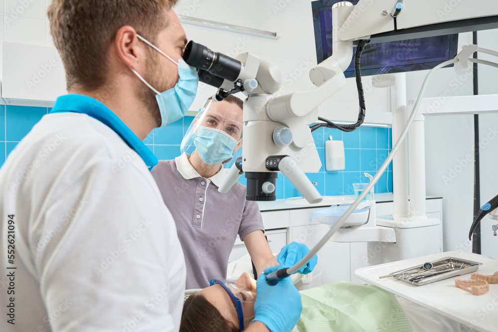 Female nurse assisting doctor during treatment of patient teeth Female nurse assisting doctor during treatment of patient teeth