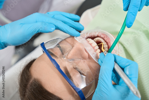 Professional dentist carrying out dental scaling on young woman