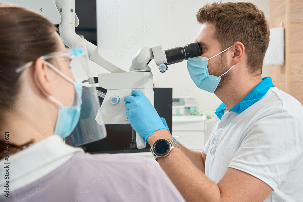 Qualified dentist adjusting modern optical instrument for work Qualified dentist adjusting modern optical instrument for work