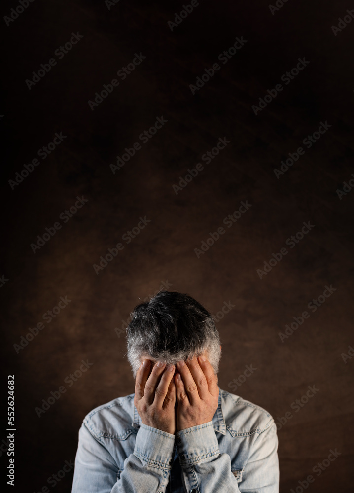 portrait d'un homme de 50 ans qui met ses mains sur son visage en signe de fatigue ou de tristesse. concept de dépression et de solitude. Large place pour le texte. portrait d'un homme de 50 ans qui met ses mains sur son visage en signe de fatigue ou de tristesse. concept de dépression et de solitude. Large place pour le texte.