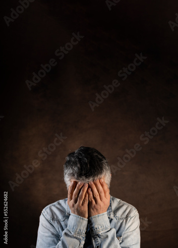 portrait d'un homme de 50 ans qui met ses mains sur son visage en signe de fatigue ou de tristesse. concept de dépression et de solitude. Large place pour le texte. © Tof - Photographie