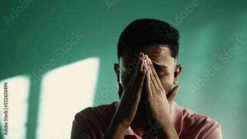 Desperate young man feeling hopeless and despair. A hispanic South American person crying covering face with hand 2