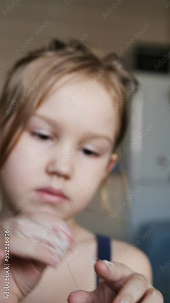 A cute caucasoid preschooler glued her fingers together with chewing gum when she played. The child cannot unstick the fingers of the palm due to sticky chewing gum. Portrait, DOF, vertical video, A cute caucasoid preschooler glued her fingers together with chewing gum when she played. The child cannot unstick the fingers of the palm due to sticky chewing gum. Portrait, DOF, vertical video,