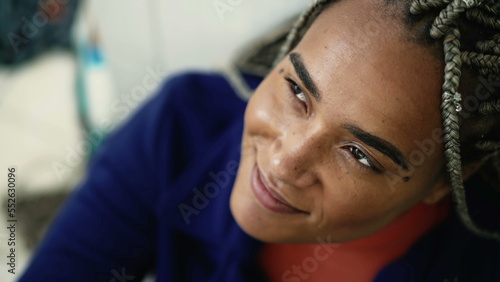 One young hispanic black woman opening eyes in contemplation. Meditative Brazilian latin adult girl closeup looks at sky feeling gratitude