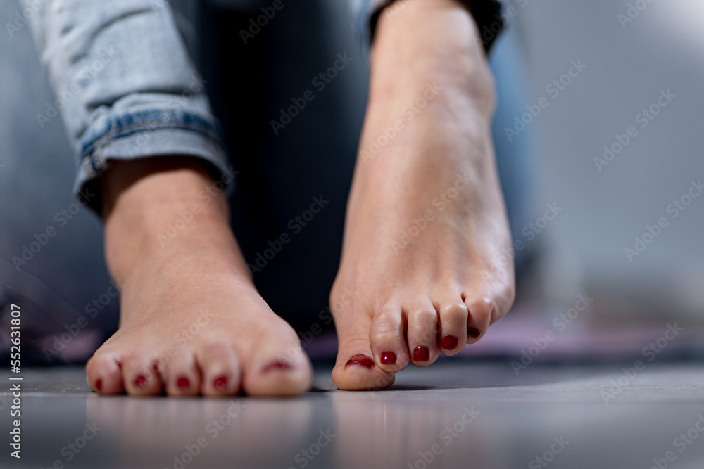 Sexy woman feet with red nail polish and a blue jeans Photos | Adobe Stock