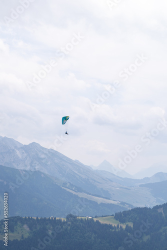 Paraglider flying over mountains on a overcast day in Le Grand-Bornand, french alps.