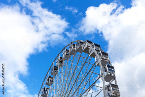 Ferris wheel against the background of white clouds and sky