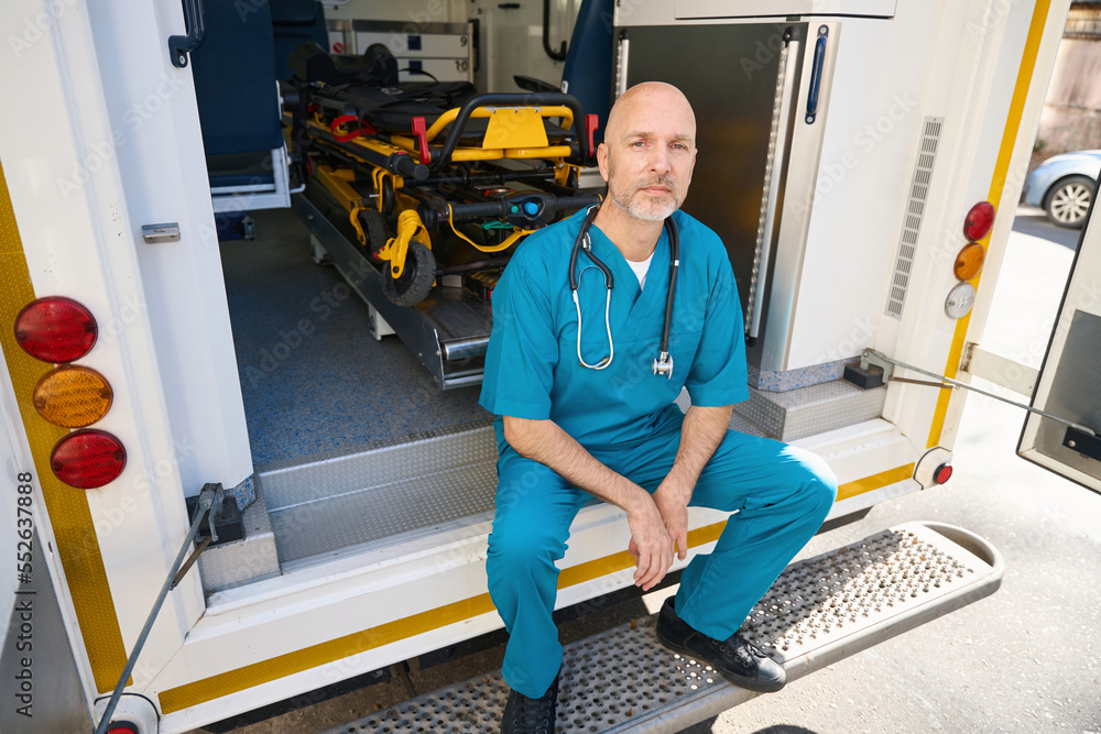 Medical officer sits near the open cockpit of a car Medical officer sits near the open cockpit of a car