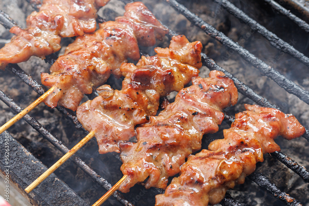 Grilled pork skewers on the stove with smoke. Traditional Thai-style grilled pork. Delicious and popular menu. Thai called 'Moo Ping'. Close-up photo. Asia food, Thai food.