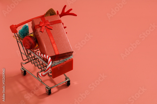 Christmas decorations in a cart, gifts, Christmas tree, red gold christmas ball and Santa's Cane isolated on red background with copy space. Christmas, winter, new year concept. close up, top view.